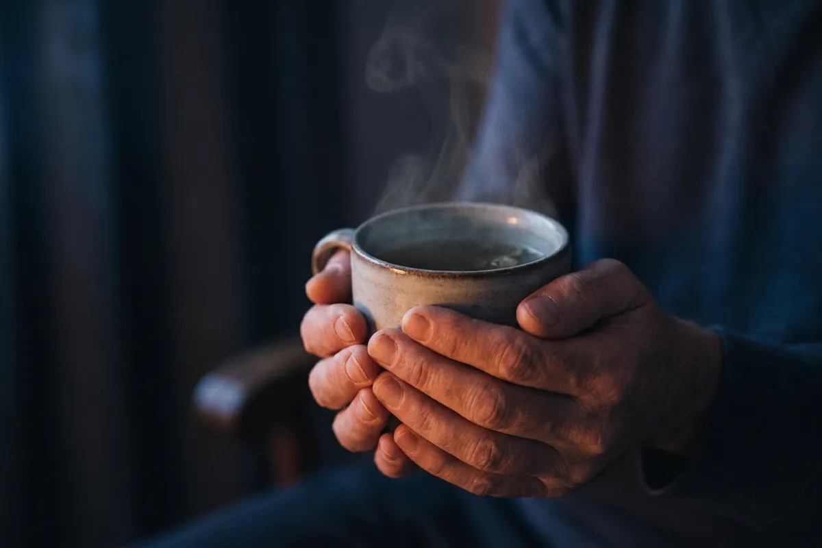 Une tasse chaude tenue à deux mains